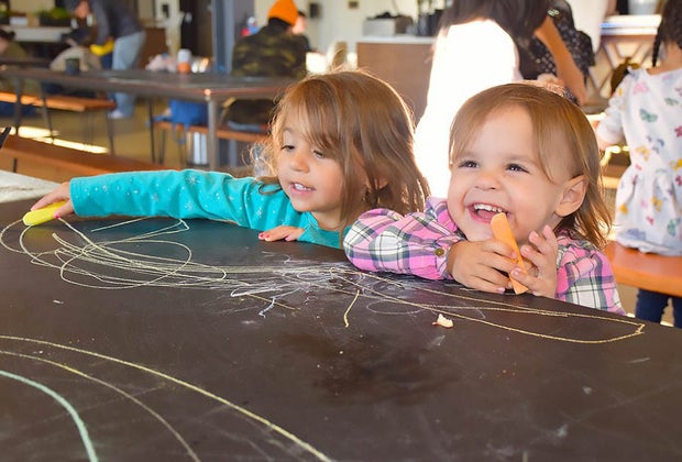 Two girls laughing and drawing at the Social Pay Haus Play Spaces on Long Island Open Now