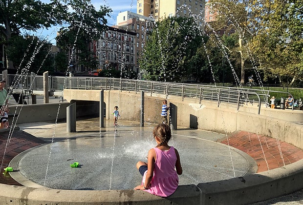 Girl perched on edge of water feature in Central Park's Tarr Family Playground
