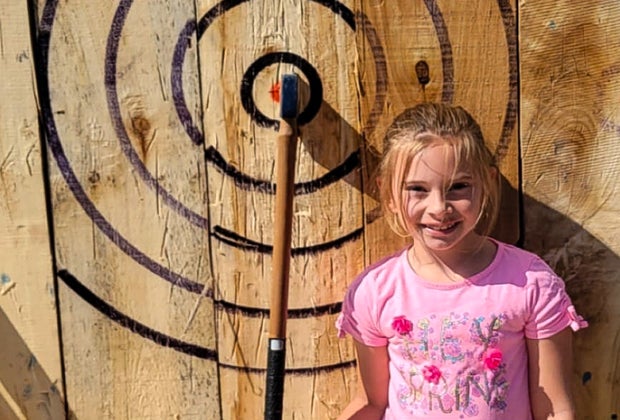 Image of child next to an axe throwing target.
