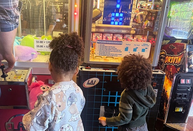 two young kids trying to win prizes at the claw machines at Square Peg Pizzeria