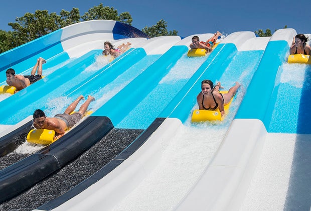 people slide down the big wave racer slides at the water park