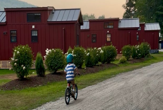 Image of child on bicycle at campsite with RVs and cabins