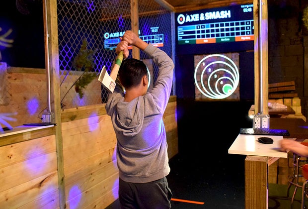 LI teens throw an axe at a wooden target at Axe & Smash.