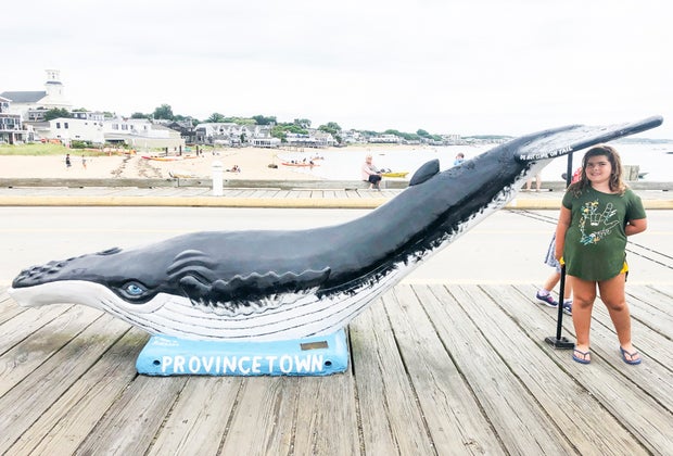 Photo of young woman with whale statue on Cape Cod.