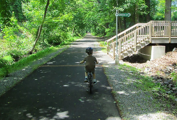 Little boy rides a bike path on the Middlesx Greenway