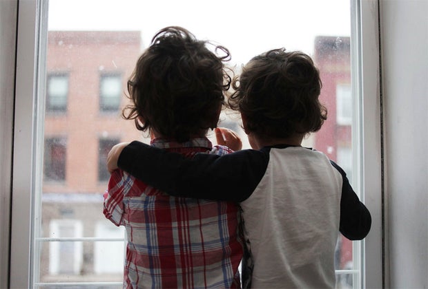 two boys looking out a window with their arms around each other