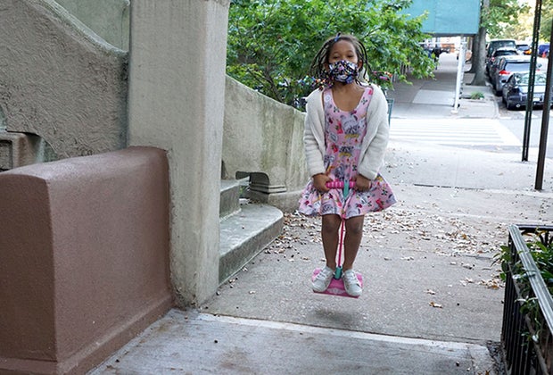 girl jumping on pogo stick on the sidewalk