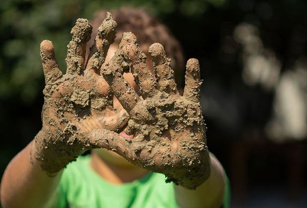 Kid with hands all muddy from playing