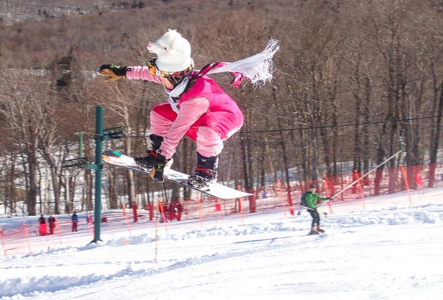 Image of snowboarder jumping on slope at New England ski resort.