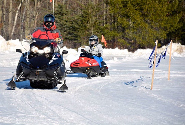 Photo of adult on snowmobile and a child on a mini-snowmobile