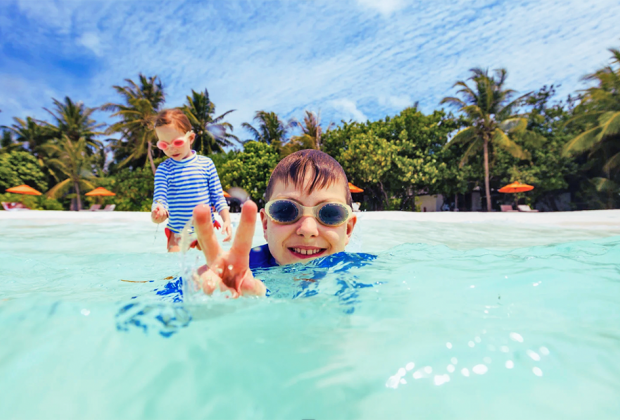 A shallow, crystal-clear Maldives lagoon is the perfect place for kids to swim.
