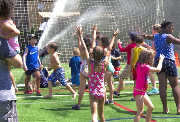 Slip and slide your way to smiles during Asphalt Green's Sprinkler Day. Photo courtesy of Asphalt Green