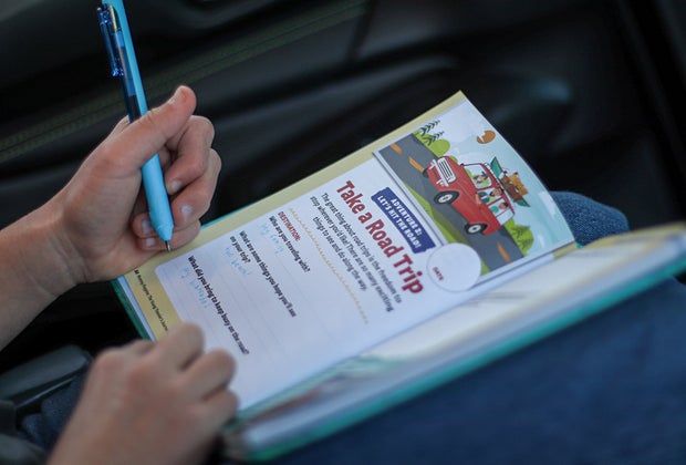 Photo of a child working on The Young Traveler’s Journal and Activity Book in the car on a road trip