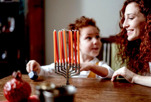 Child lighting candles for Hanukkah on a menorah